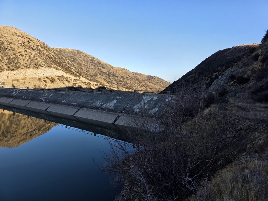 Falls Dam Redevelopment — concrete dam wall reflected in the still reservoir