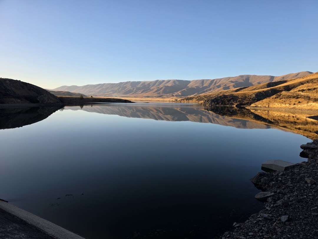 Falls Dam Redevelopment — calm reservoir water mirroring the Manuherikia hills